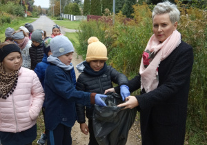 dzieci wrzucają znalezione śmieci do worka
